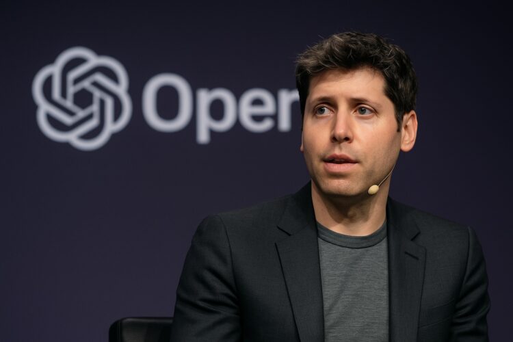 Sam Altman habla en un panel con el logo de OpenAI proyectado en pantalla LED detrás