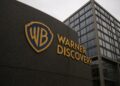 Fachada moderna de Warner Bros. Discovery con su logotipo dorado destacado en primer plano.