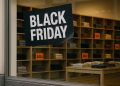Vidriera de tiendas minoristas con cartel de Black Friday y estantes llenos tras el evento.