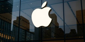 Logo iluminado de Apple en la fachada de una tienda mientras la marca lidera el ajuste en Big Tech.