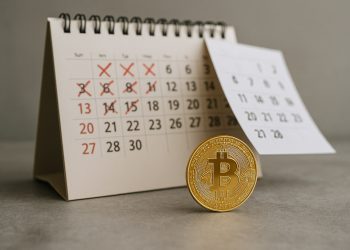 Moneda física de Bitcoin frente a un calendario con días tachados, sugiriendo rebote tras un mes difícil.