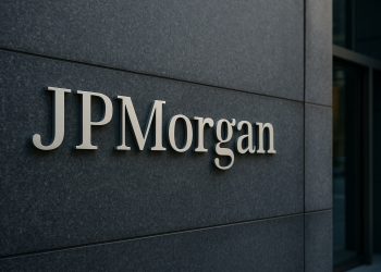 Logo de JPMorgan en gran placa metálica sobre muro oscuro, protagonista de la escena.