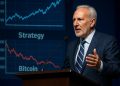 Peter Schiff habla en conferencia con gráficos de Strategy y caída de Bitcoin proyectados detrás