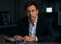 Toto Wolff en oficina moderna junto a un modelo metálico de F1 con detalles tecnológicos sutiles.