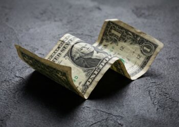 Billete de dólar estadounidense arrugado sobre superficie oscura colapso.