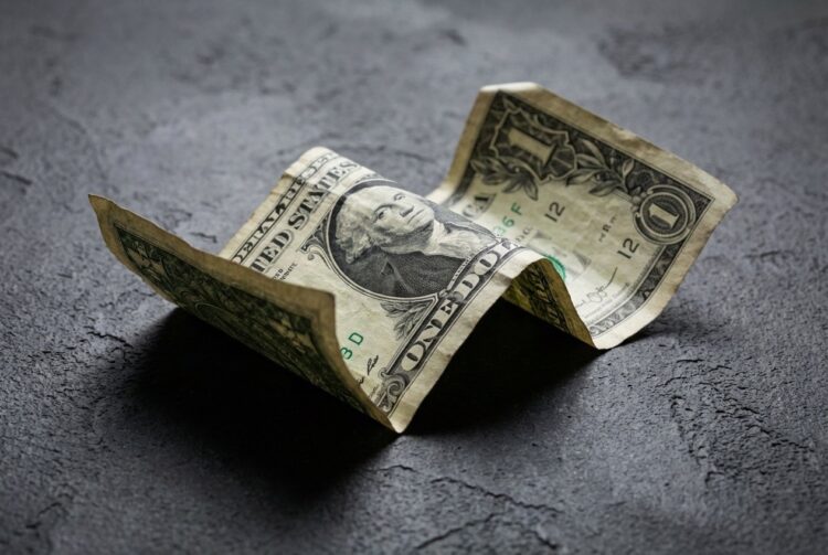 Billete de dólar estadounidense arrugado sobre superficie oscura colapso.