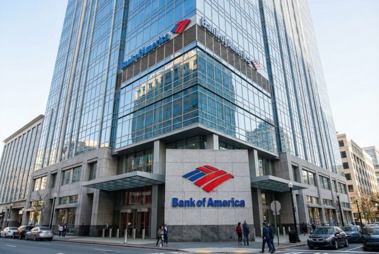 Fotografía corporativa exterior en un ángulo dinámico de tres cuartos de la torre sede de Bank of America en Charlotte. El logotipo de la bandera roja y azul y las letras 'Bank of America' son muy visibles sobre la señalización de piedra en la entrada a nivel de calle y en la parte superior de la fachada de vidrio reflectante bajo la luz del día.