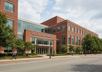 Vista exterior frontal del edificio principal de la sede corporativa de Eli Lilly and Company en Indianápolis. La arquitectura de ladrillo rojo y vidrio se ve nítida bajo la luz del día y el letrero con el nombre de la empresa es claramente visible en la entrada, transmitiendo solidez y presencia institucional en la industria farmacéutica.
