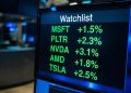 Primer plano de monitor financiero mostrando una lista de vigilancia con tickers tecnológicos en verde y alzas.