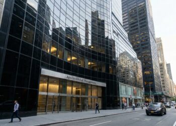 Fotografía de la fachada de vidrio del edificio de oficinas de Apollo Global Management en la ciudad de Nueva York. El letrero de la empresa es visible sobre la entrada principal, con peatones caminando por la acera y vehículos en la calle.