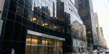 Fotografía de la fachada de vidrio del edificio de oficinas de Apollo Global Management en la ciudad de Nueva York. El letrero de la empresa es visible sobre la entrada principal, con peatones caminando por la acera y vehículos en la calle.