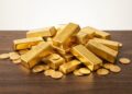 Primer plano lingotes y monedas oro precio máximo histórico.