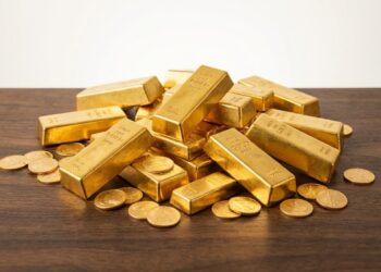 Primer plano lingotes y monedas oro precio máximo histórico.