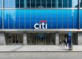Fachada de la sede de Citigroup en 388 Greenwich St, NY, con el logo azul y rojo sobre la entrada principal y peatones caminando.