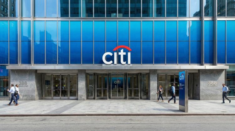 Fachada de la sede de Citigroup en 388 Greenwich St, NY, con el logo azul y rojo sobre la entrada principal y peatones caminando.