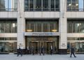 Entrada principal de la sede de JPMorgan Chase en 383 Madison Ave, NY; profesionales entran y salen.