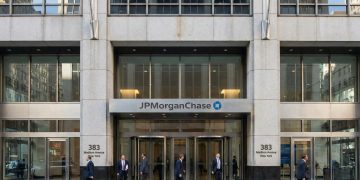 Entrada principal de la sede de JPMorgan Chase en 383 Madison Ave, NY; profesionales entran y salen.