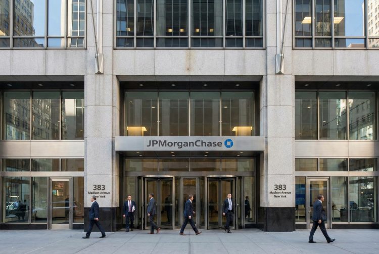 Entrada principal de la sede de JPMorgan Chase en 383 Madison Ave, NY; profesionales entran y salen.