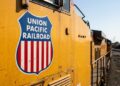 Logo Union Pacific en locomotora amarilla, proyección de ganancias 2026.