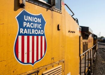 Logo Union Pacific en locomotora amarilla, proyección de ganancias 2026.