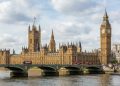 Fotografía diurna del Palacio de Westminster y la Torre Elizabeth (Big Ben) a través del río Támesis, con el puente de Westminster y un cielo parcialmente nublado.