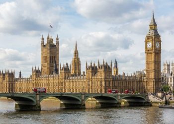 Fotografía diurna del Palacio de Westminster y la Torre Elizabeth (Big Ben) a través del río Támesis, con el puente de Westminster y un cielo parcialmente nublado.