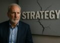 Peter Schiff posa serio junto a un gran logo de Strategy agrietado en la pared.