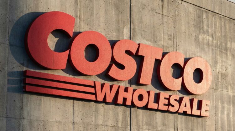 Gran letrero rojo y texturizado de Costco Wholesale sobre muro de concreto.