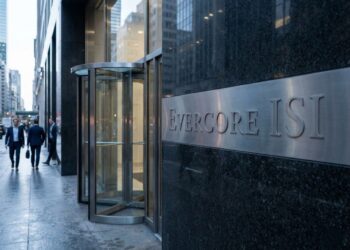 Fotografía de estilo editorial arquitectónico que captura la entrada del edificio de Evercore ISI. En primer plano, una placa de metal cepillado con el texto grabado "EVERCORE ISI" está montada sobre una pared de granito oscuro pulido. Al fondo, se ve una puerta giratoria de cristal y varias personas vestidas con trajes de negocios caminando por la acera mojada, reflejando la luz suave de la mañana urbana.