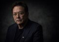 Retrato serio de Robert Kiyosaki en fondo oscuro editorial financiero.