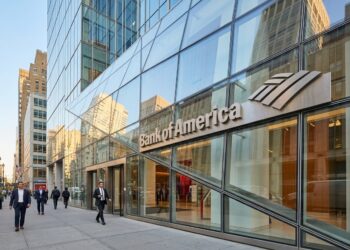 Entrada de la sede de Bank of America en NYC con el logotipo metálico en la fachada de vidrio, bajo la luz de la mañana.