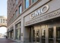 Toma exterior de la entrada de la oficina de GMO en Rowes Wharf, Boston, con un letrero grande y un arco al fondo que da al puerto.