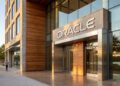 Fotografía de la entrada de Oracle en The Waterfront, Austin, con fachada de madera, piedra y letrero luminoso 'ORACLE'.