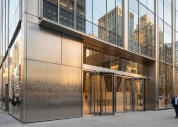 Fachada de metal y cristal con el logo grabado de JPMorgan Chase. Personas caminando afuera.