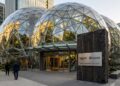 Tres grandes cúpulas de vidrio de las Amazon Spheres con un letrero de colaboración con OpenAI. Personas de negocios en la acera.
