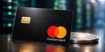Tarjeta Mastercard junto a moneda digital sobre mesa.
