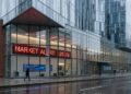 Edificio de Circle Internet Financial con gran pantalla que muestra 'MARKET ALERT: -20.0%'. Peatones con paraguas en día lluvioso.
