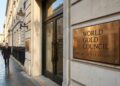 Profesionales financieros caminan frente a la entrada de la sede de Londres del World Gold Council con un prominente letrero de bronce.