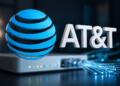 Logo de AT&T en primer plano con router y fibra al fondo.