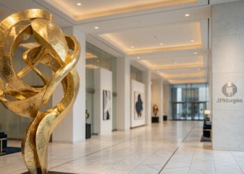 Lobby de JPMorgan con gran escultura dorada abstracta y suelo de mármol blanco pulido.