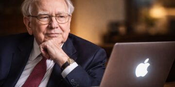Warren Buffett observando una laptop con el logo de Apple en un entorno sobrio.