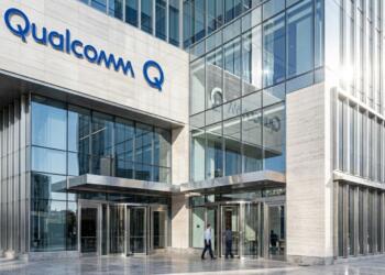 Fotografía exterior de un edificio de oficinas moderno de Qualcomm con un letrero azul en la fachada.