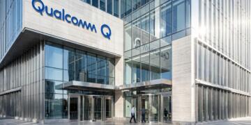 Fotografía exterior de un edificio de oficinas moderno de Qualcomm con un letrero azul en la fachada.