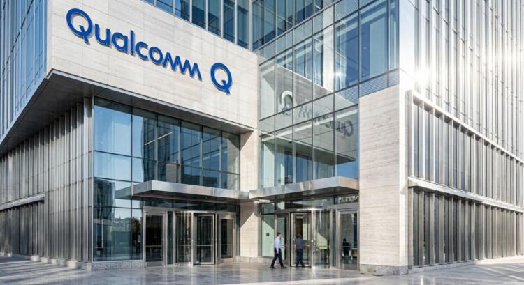 Fotografía exterior de un edificio de oficinas moderno de Qualcomm con un letrero azul en la fachada.