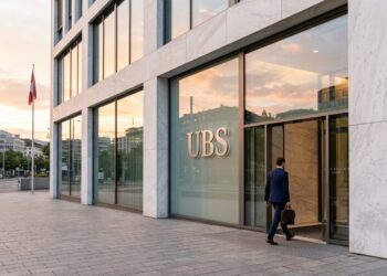 Entrada de mármol y vidrio de la sede de UBS en Zúrich durante el amanecer con un empleado entrando.