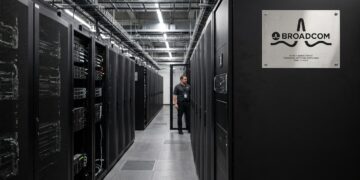 Un largo pasillo de servidores negros mate en un centro de datos de Google Cloud, con una placa de identificación de acero cepillado de Broadcom.