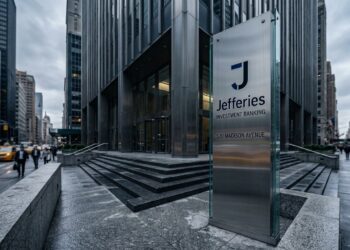 Entrada de Jefferies con logo en pilar de acero y vidrio en 520 Madison Avenue, Nueva York.
