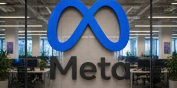 Logo de Meta en gran formato con oficina corporativa desenfadada al fondo.