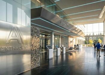 Vestíbulo de oficinas moderno con logos de Anthropic y Google Cloud y quioscos de autoservicio.