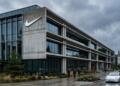 Fachada de concreto y vidrio de un edificio de Nike con un gran logo de la marca.